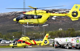 Bildet viser et ambulansehelikopter som er i ferd med &aring; lette, og et som st&aring;r p&aring; bakken i bakgrunnen