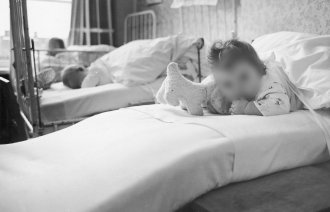 Bildet viser et lite barn som ligger i en sykehusseng.