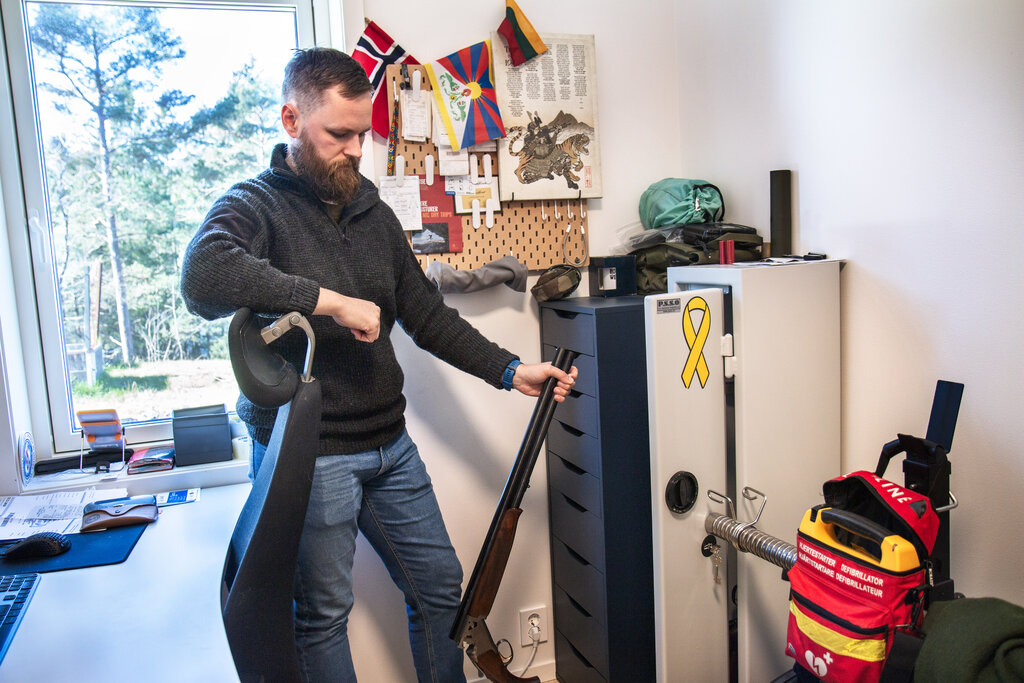 Bildet viser sykepleier Max-Hendrik Wathne Gelink på kontoret med jaktvåpen