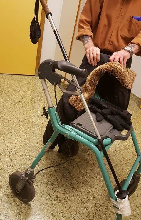 rullatortriks Bildet viser en rullator som har en innretning laget av teip og plastkrus som man kan sette en gåstav oppi.