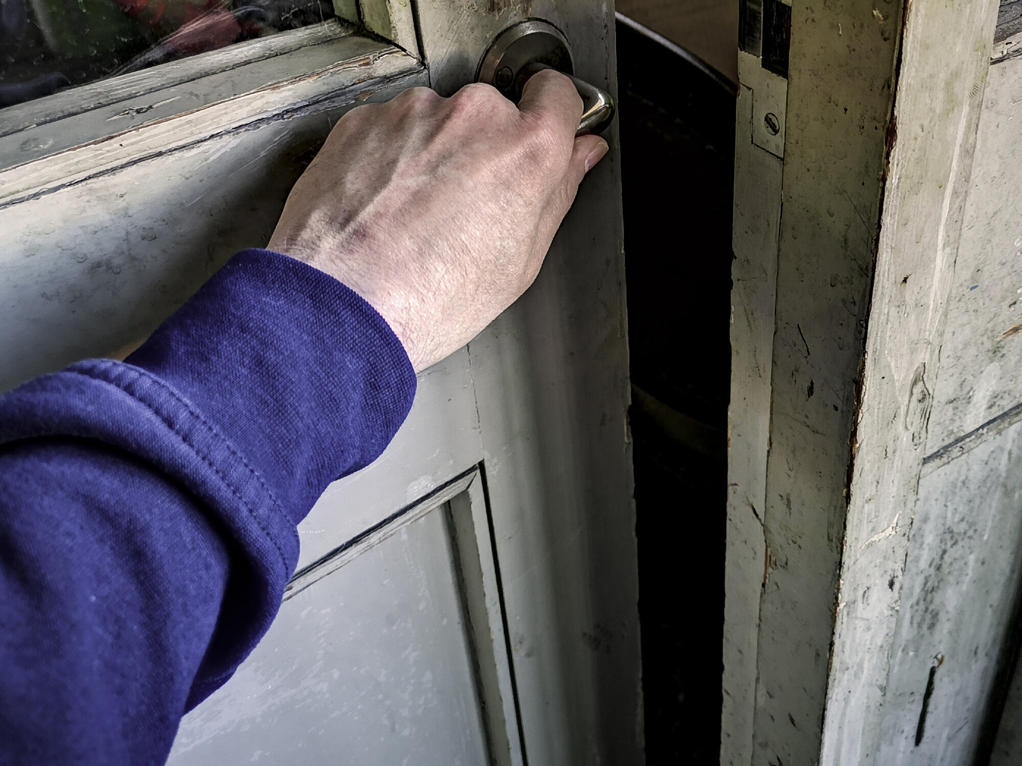 Mann lukker dør Bildet viser en arm som lukker en gammel dør