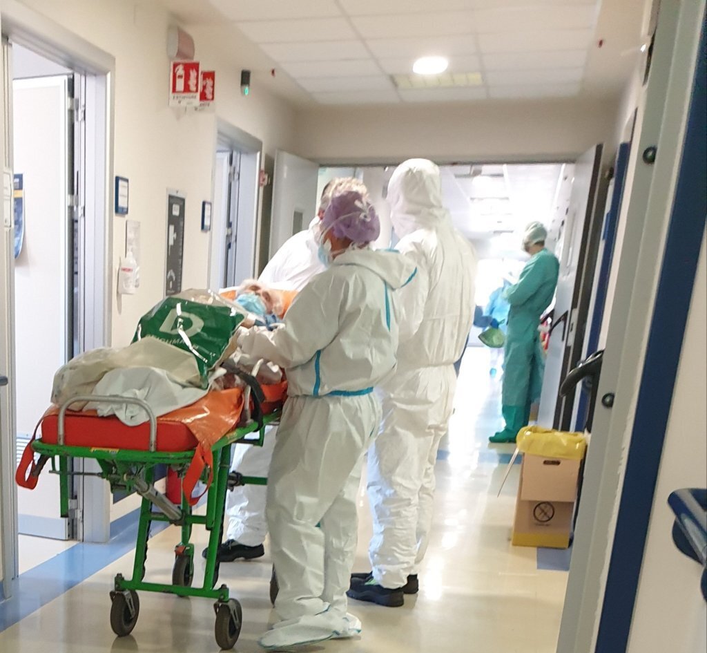 Medisinsk innsatsteam Bildet viser helsepersonell i smittevernutstyr som triller en pasient ut av en avdeling over til en annen.