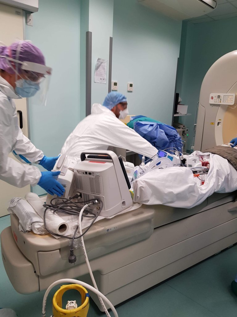 Medisinsk innsatsteam Bildet viser helsepersonell i smittevernutstyr som gjør pasient klar til CT.