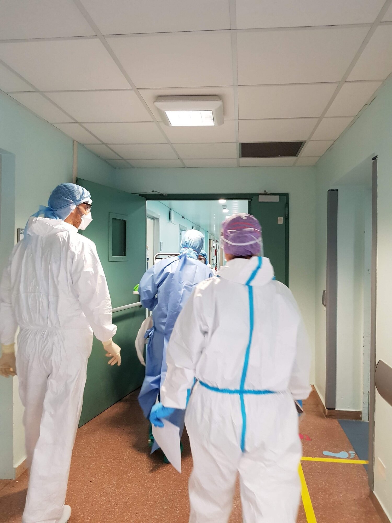 Bildet viser helsepersonell i smittevernutstyr som triller en pasient ut av en avdeling. Medisinsk innsatsteam