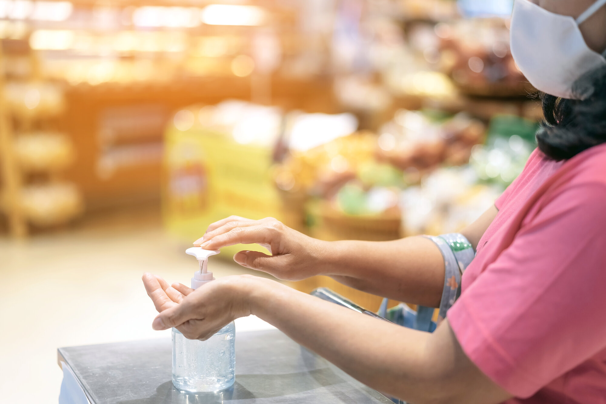 Håndsprit i butikk Bildet viser en dame som tar på håndsprit i en butikk