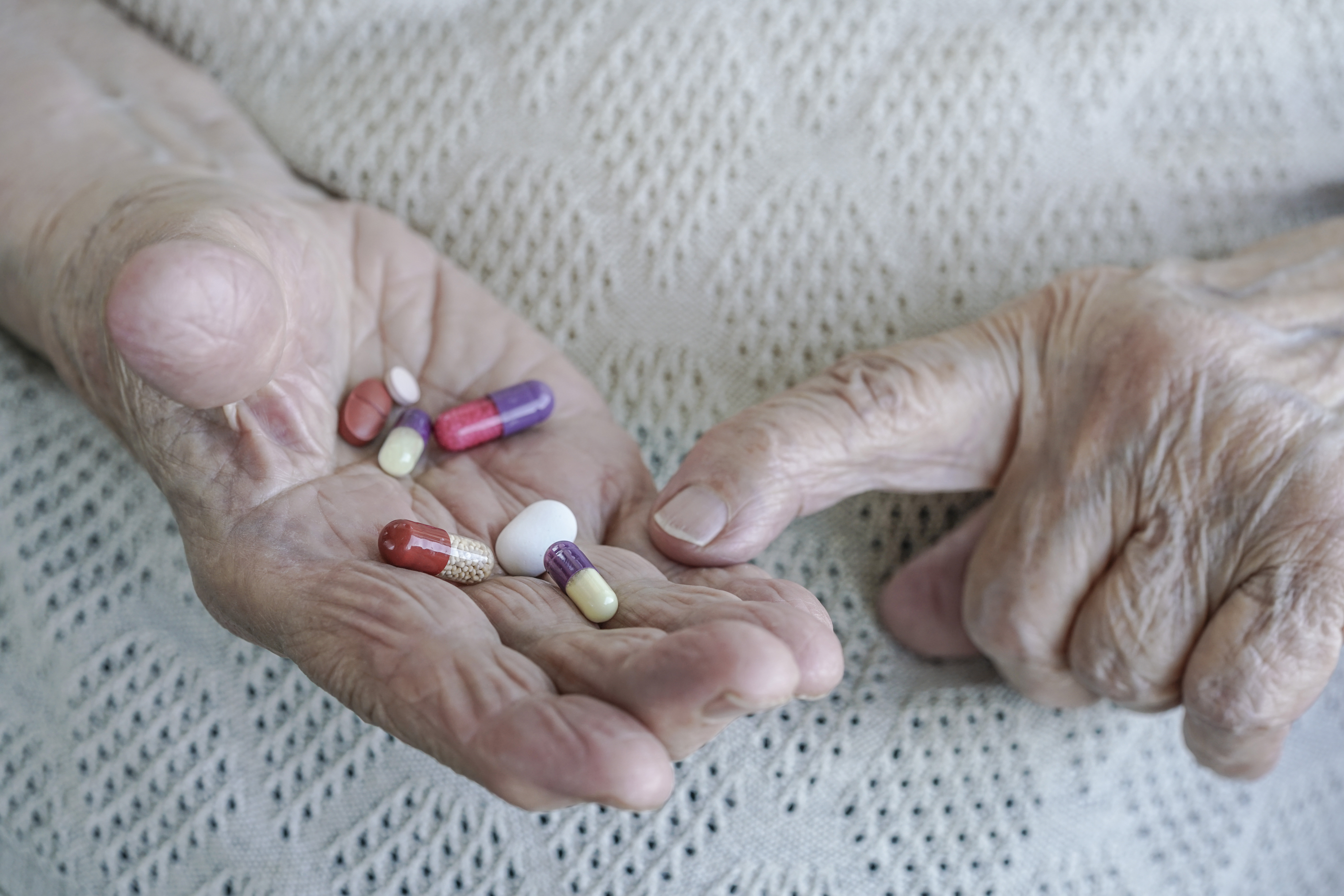 gamle hender med piller bildet viser gamle hender med piller