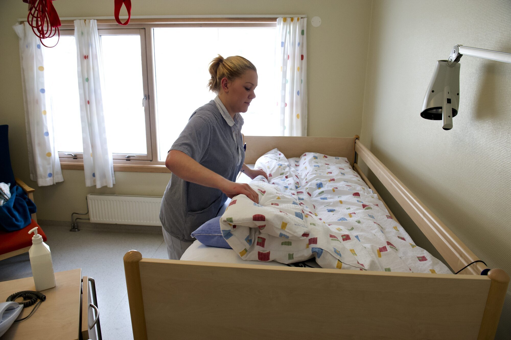 En pleier rer en sykehjemsseng. En pleier rer en sykehjemsseng.