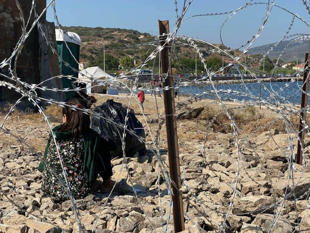 Medisinsk innsatsteam Bildet viser et menneske som sitter med ryggen til bak et nettinggjerde.