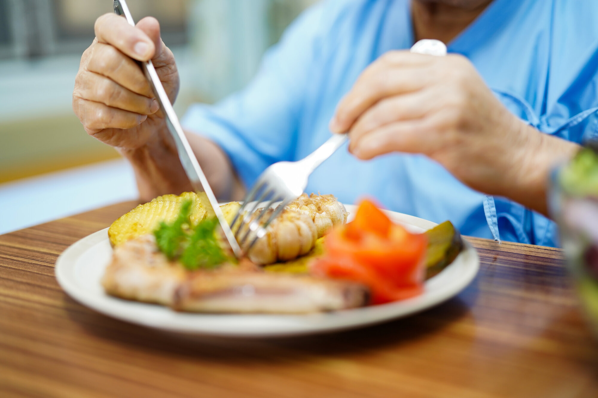 Måltid på sykehuset Bildet viser en pasient på sykehus som har en tallerken med mat foran seg