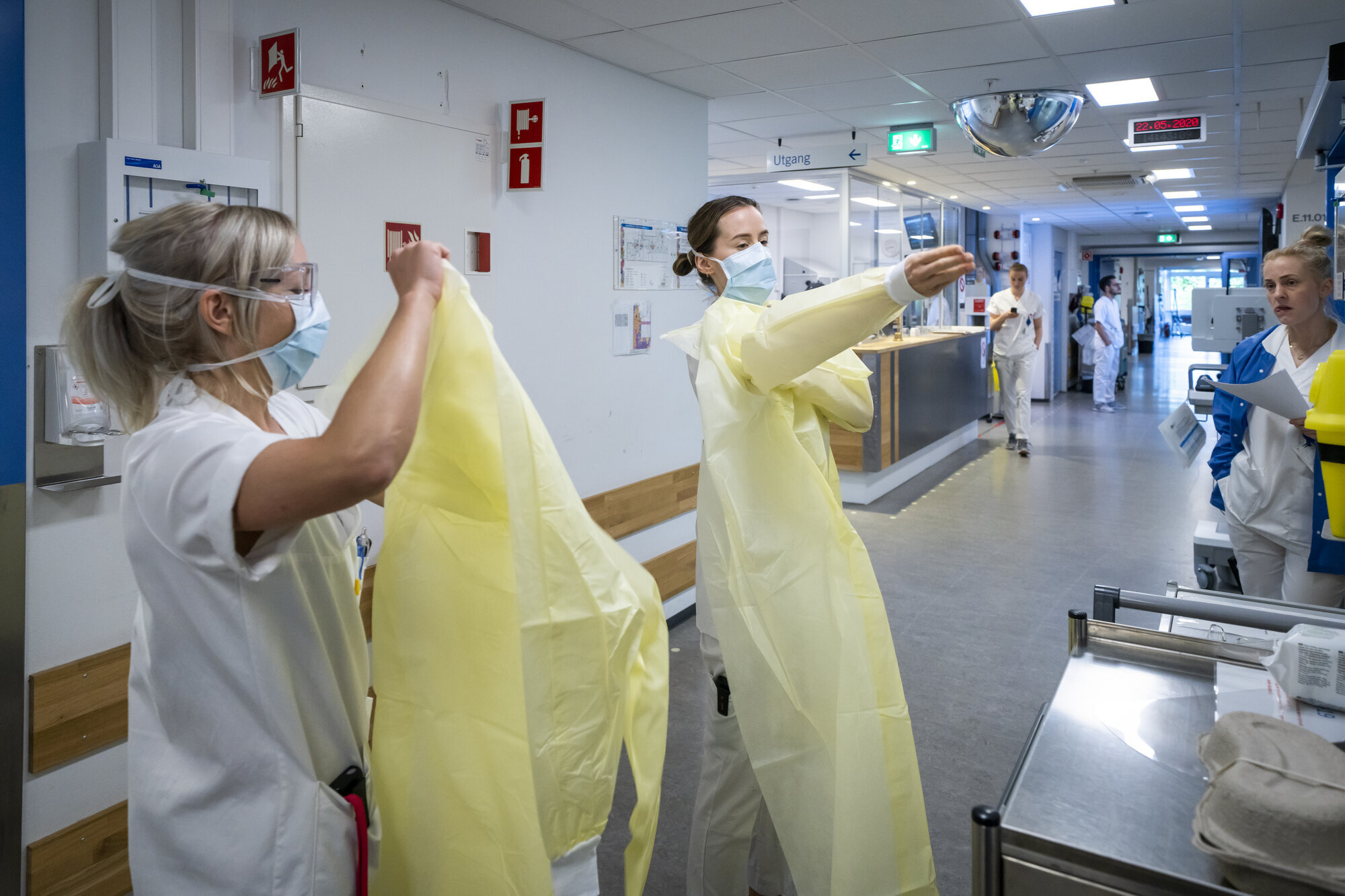 Sykepleier, smittevernutstyr Bildet viser to sykepleiere som tar på gule smittevernfrakker.