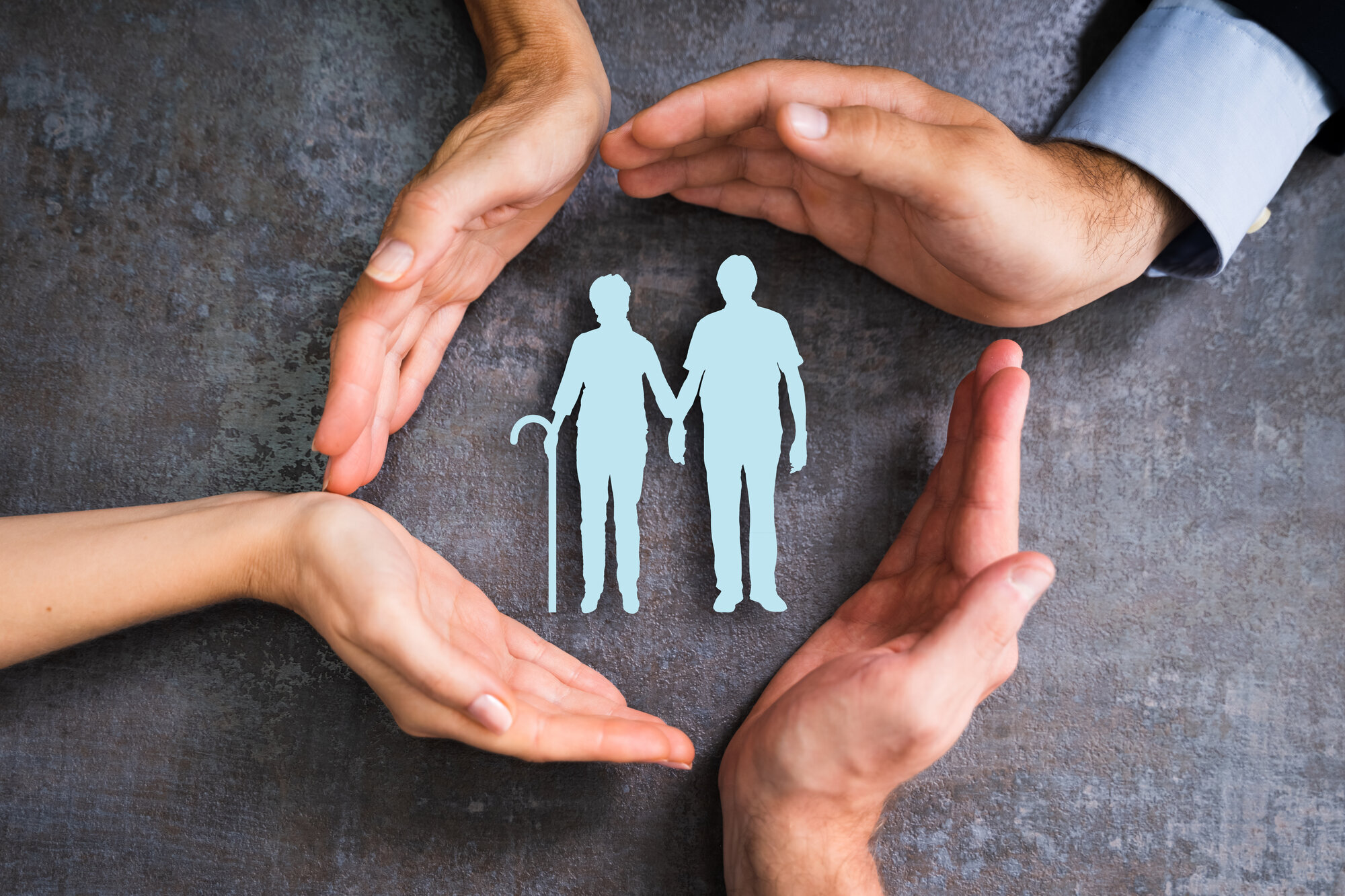 Fire hender som verner to gamle mennesker. Bildet viser fire hender som verner to gamle mennesker.