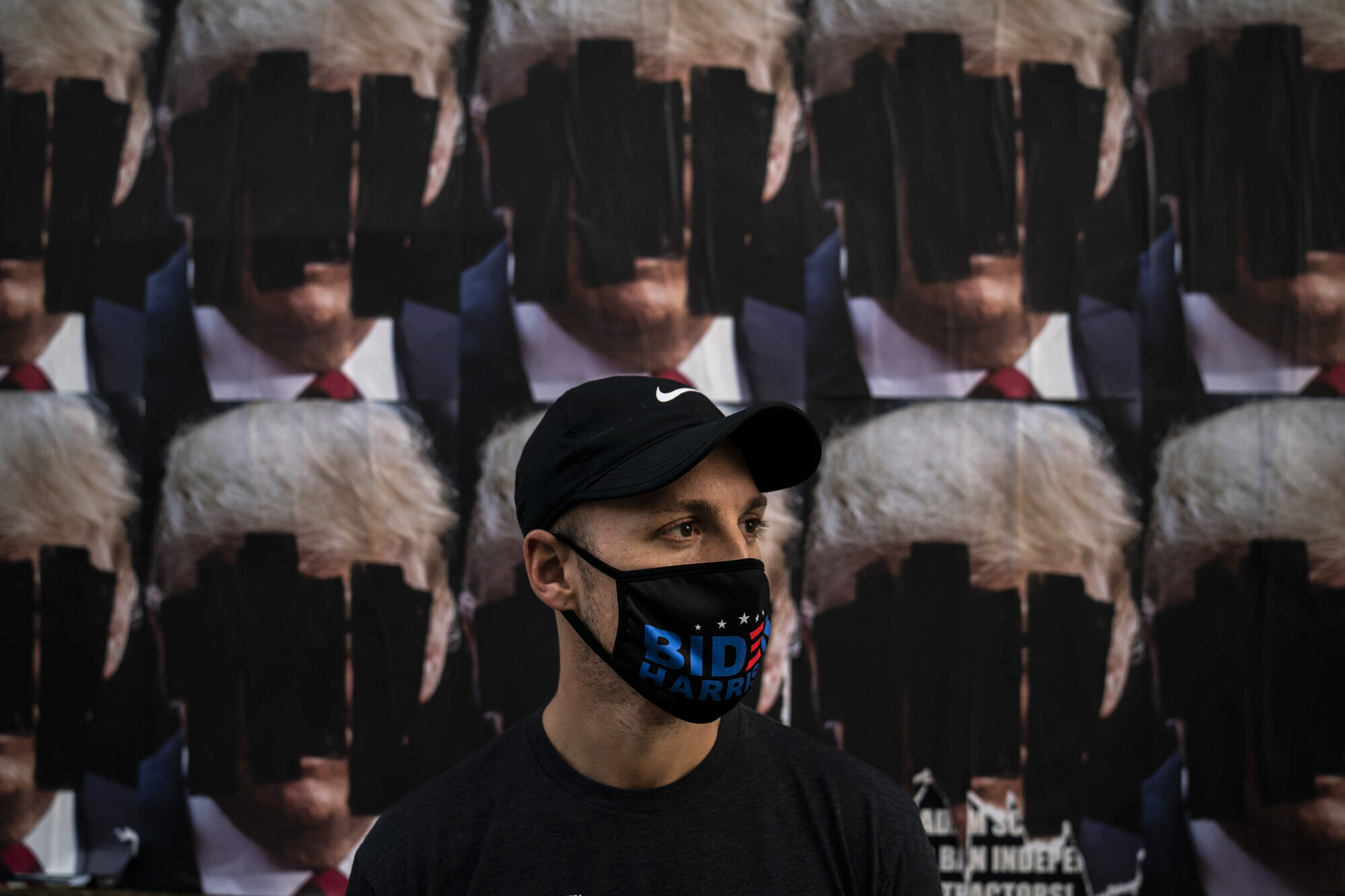USA, valg, sykepleier Bildet viser en mann med maske som det står Biden på, foran nedtusjete plakater av Trump.