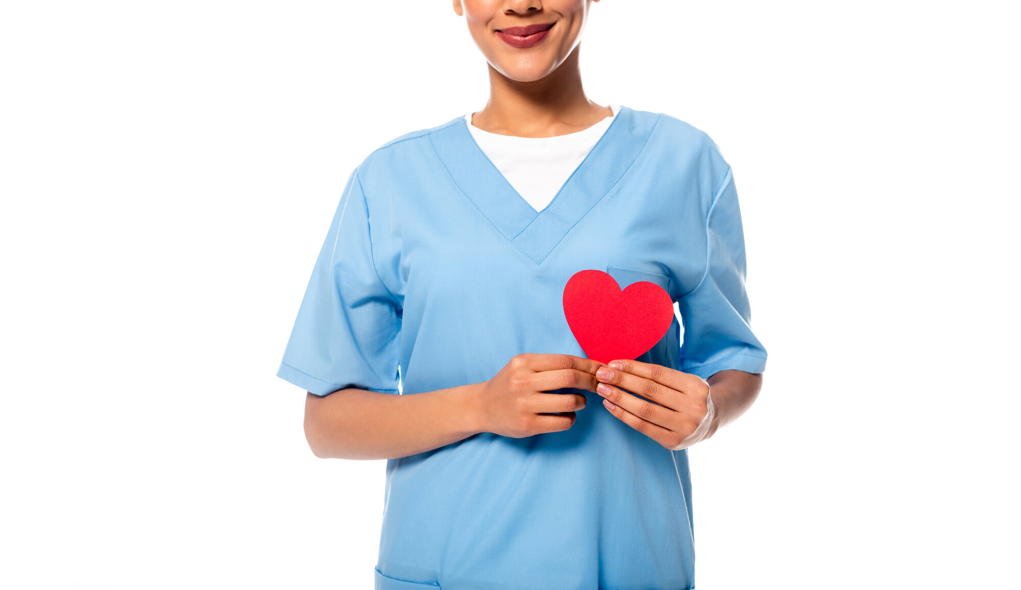 En sykepleier holder et papirhjerte foran hjertet sitt Bildet viser en sykepleier som holder et papirhjerte foran hjertet sitt