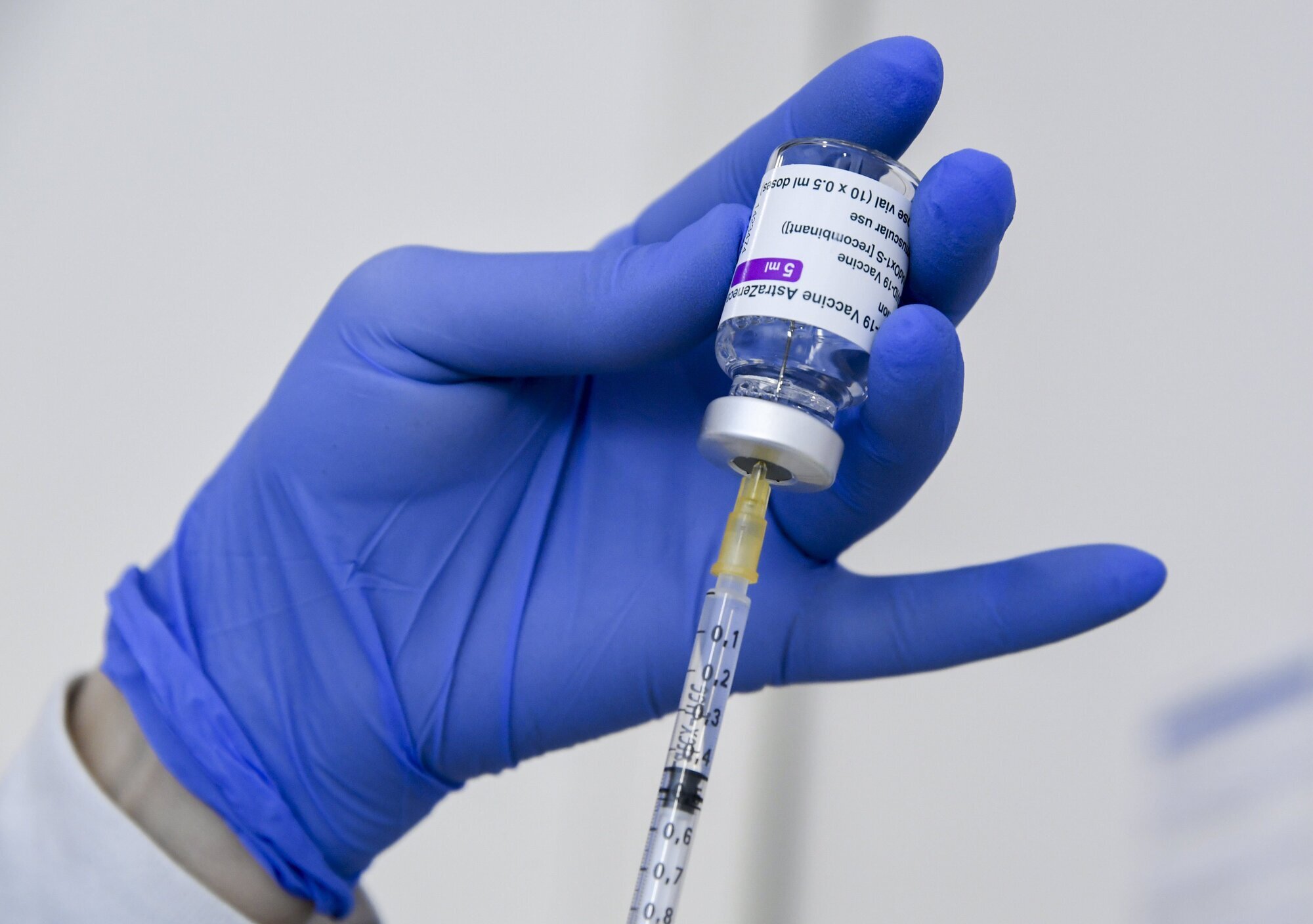 Koronavaksine Bildet viser en hånd som holder et hetteglass med koronavaksine, som det trekkes opp en dose fra.