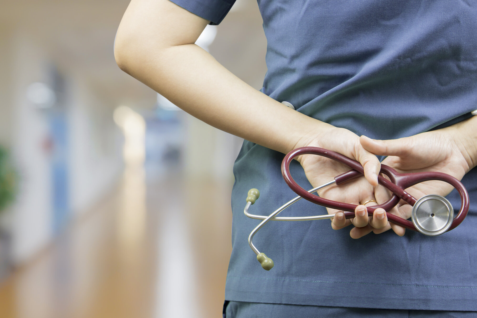 Bildet viser en helsearbeider med hendene på ryggen. Bildet viser en helsearbeider med hendene på ryggen.