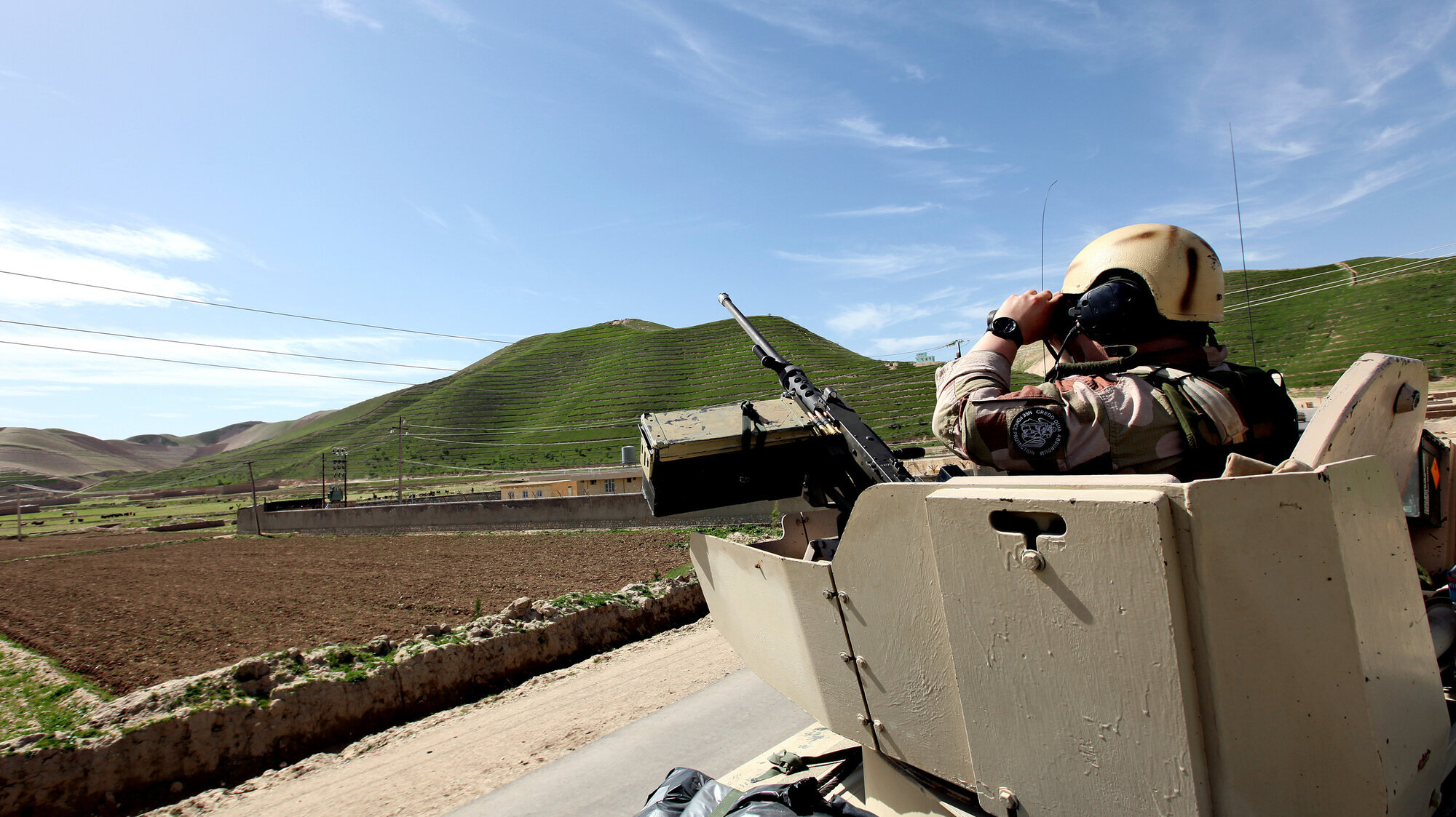 Bildet viser en tanks i Afghanistan. En norsk soldat står med kikkert opp av hullet i tanksen.
