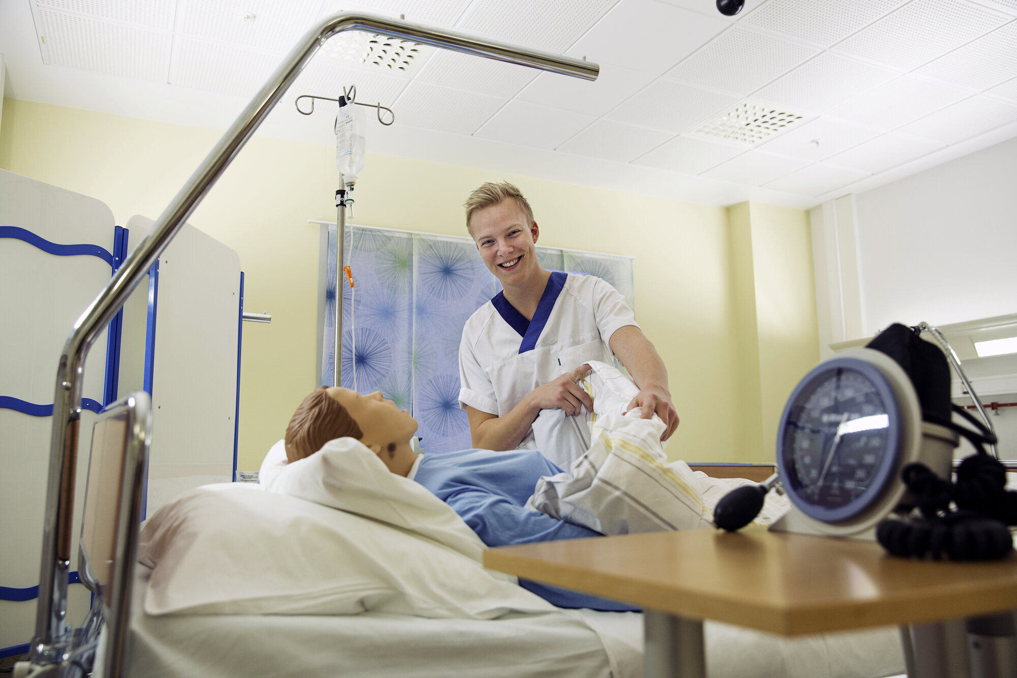 Simulering Bildet viser en sykepleierstudent som står ved siden av en seng hvor det ligger en simuleringsdukke