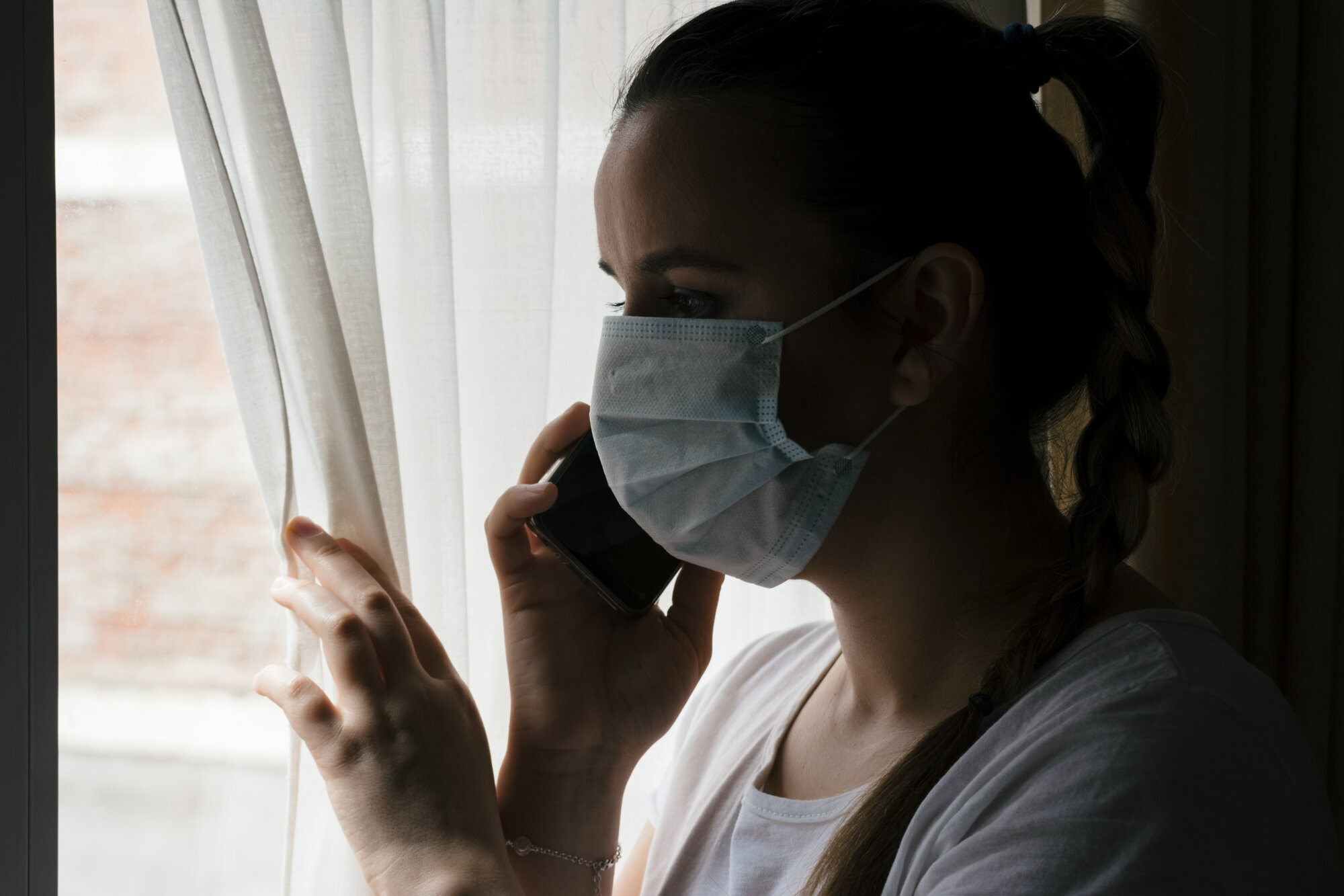 Sykepleier med munnbind Sykepleier med munnbind kikker ut av vindu