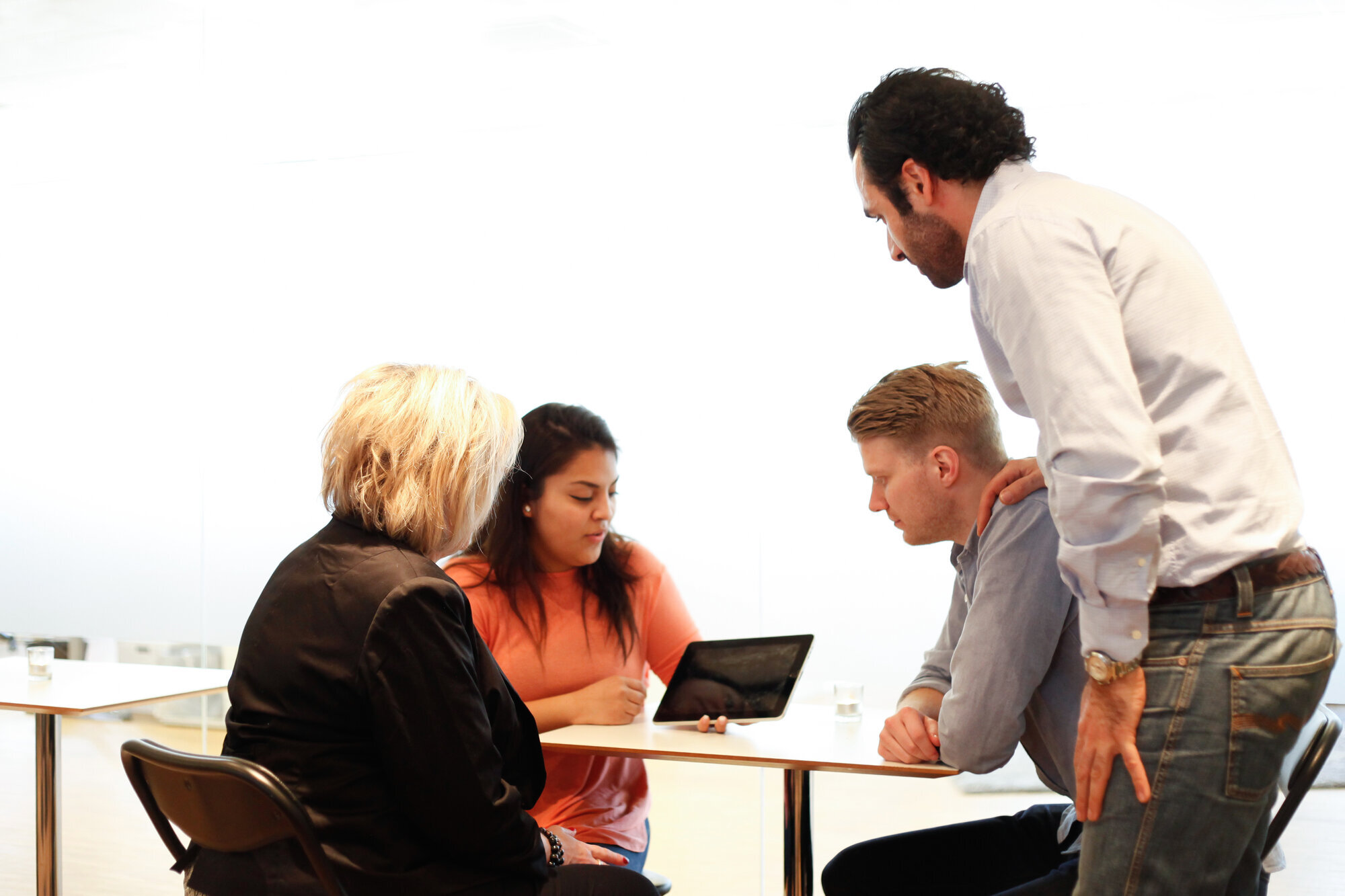 Milepålsmøte i rusbehandling Bildet viser møtedeltakere rundt et bord. En mann holder står oppe og holder hånda støttende på skulderen til en yngre mann