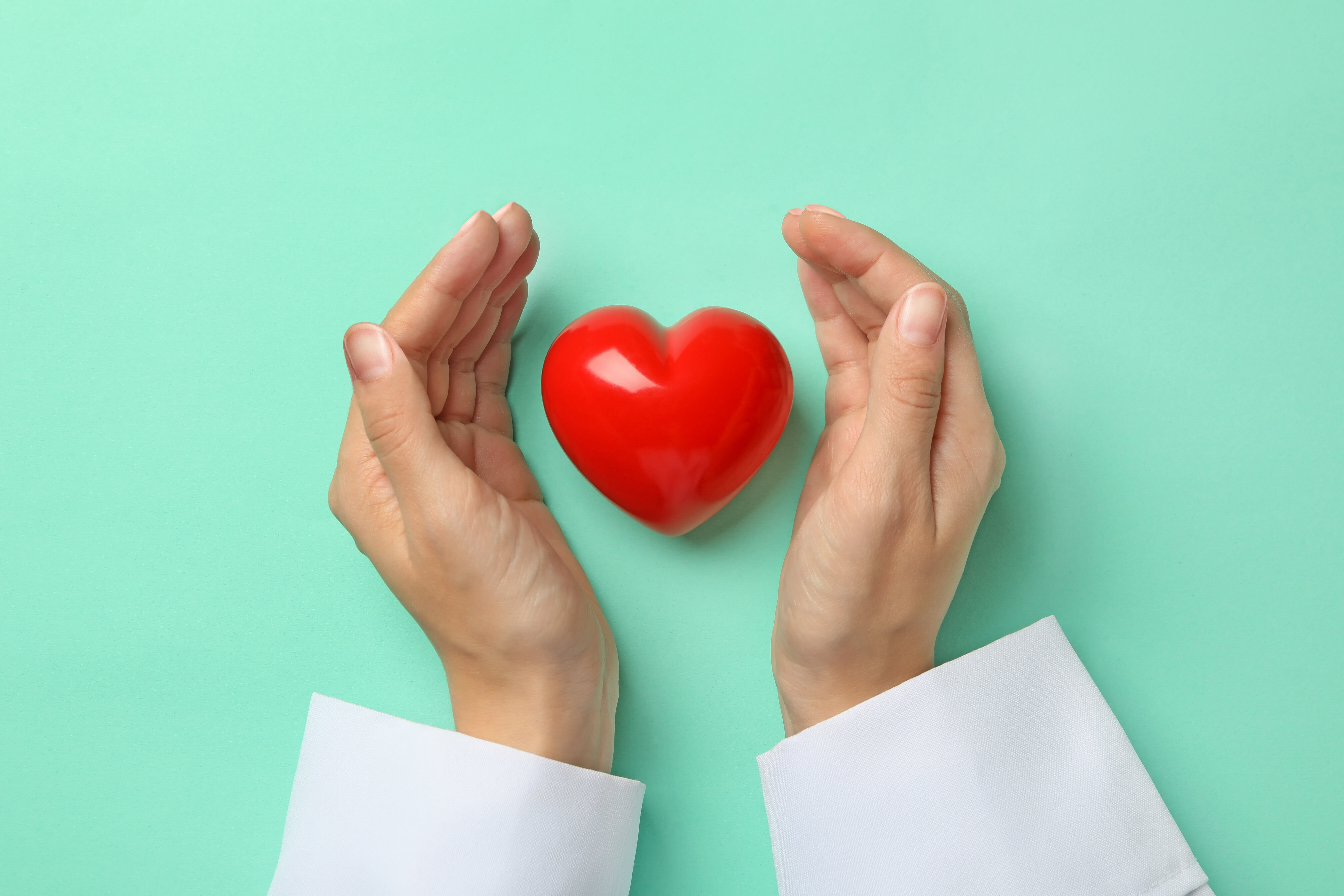 Bildet viser hendene til en sykepleier som holder rundt et hjerte