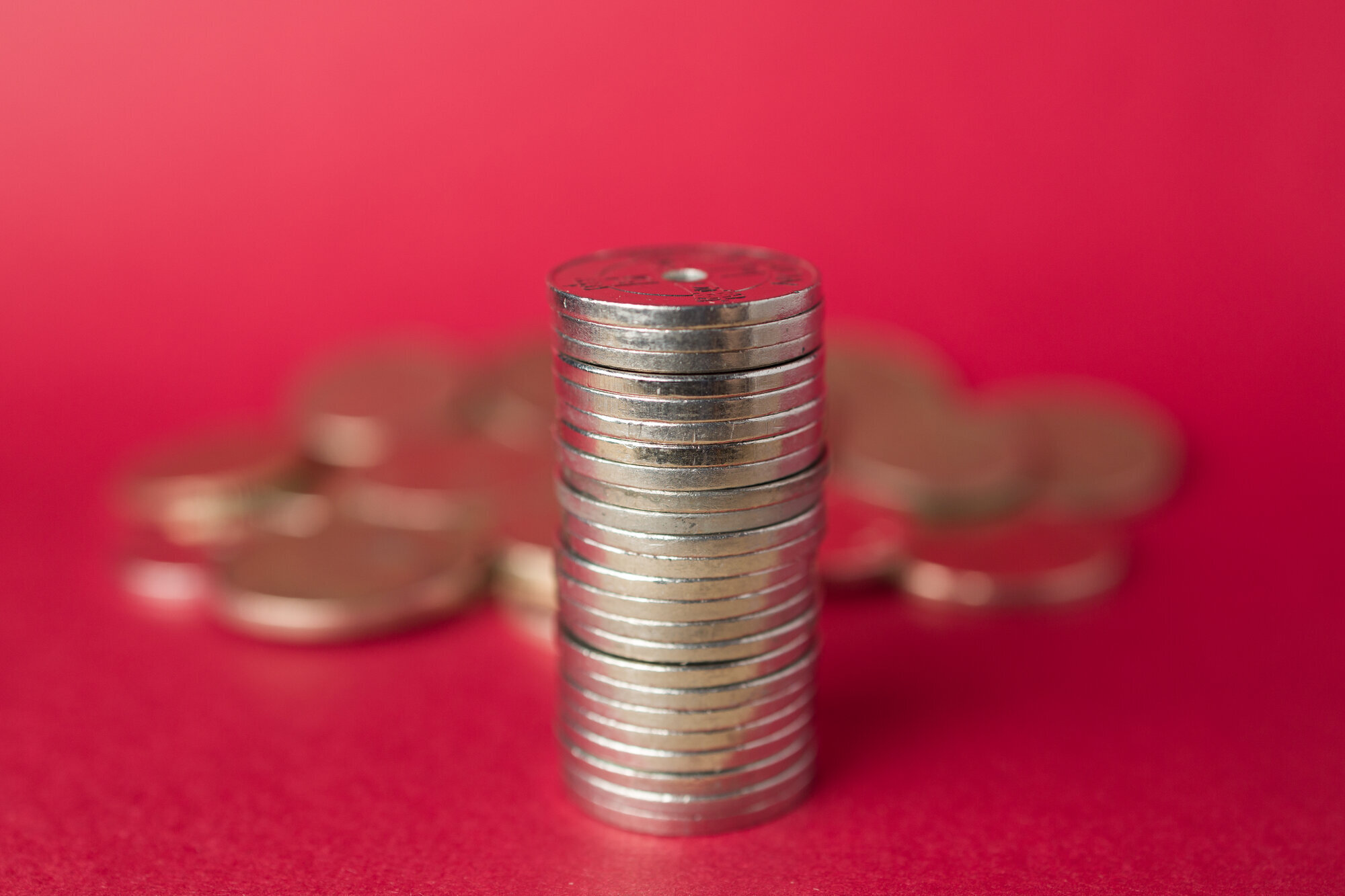 Bildet viser mynter stablet oppå hverandre på en rød bakgrunn