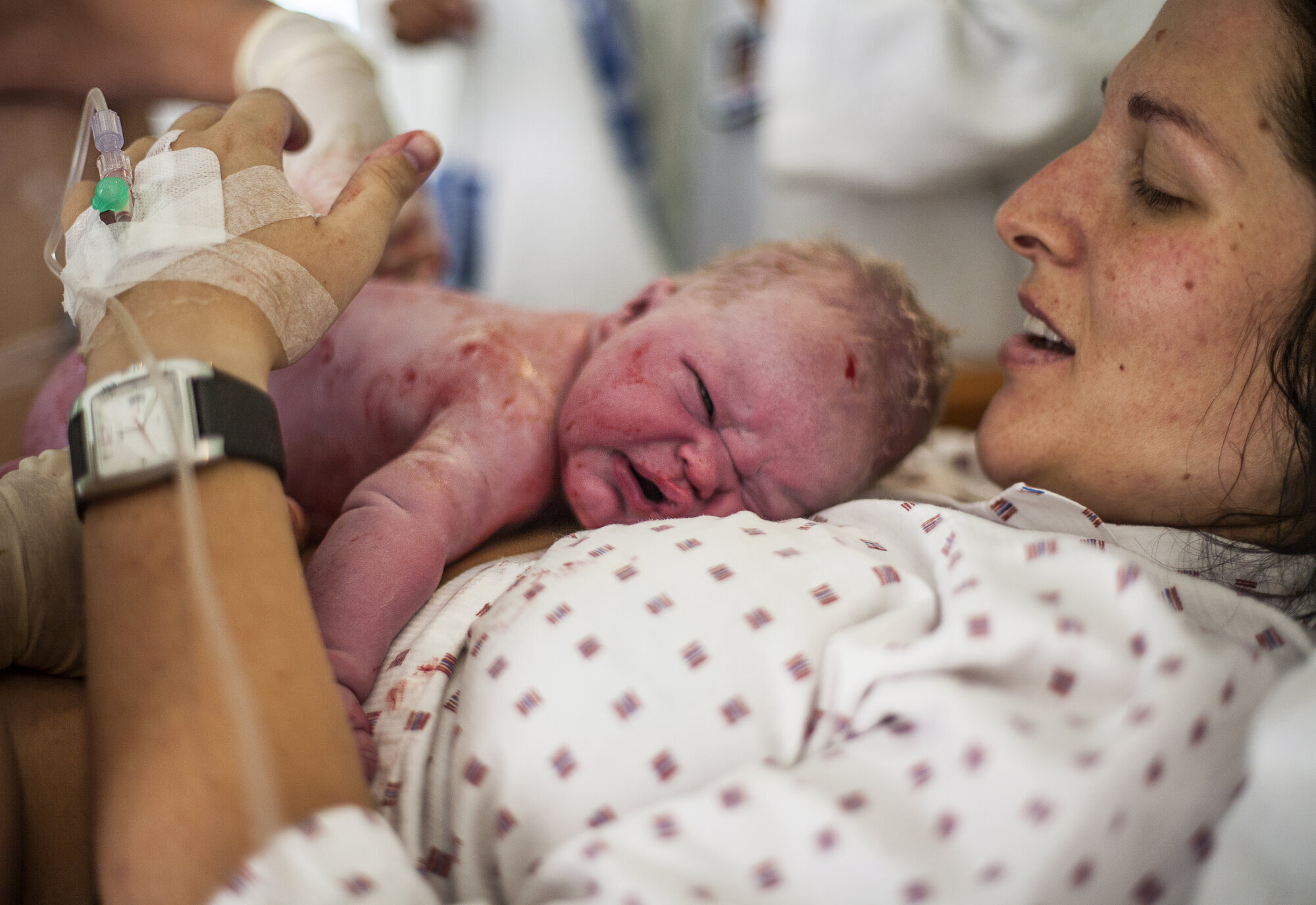 Mor med nyfødt barn Bildet viser en nyfødt baby som ligger på magen til moren