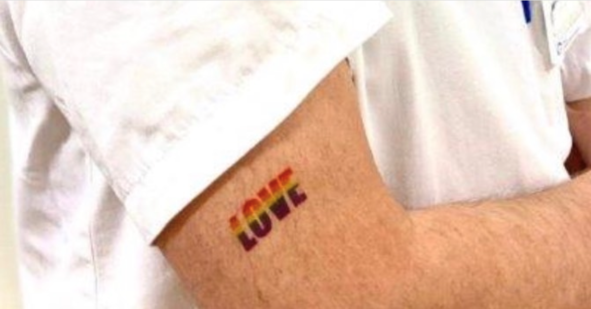 Bildet viser en arm med regnbuetatovering.