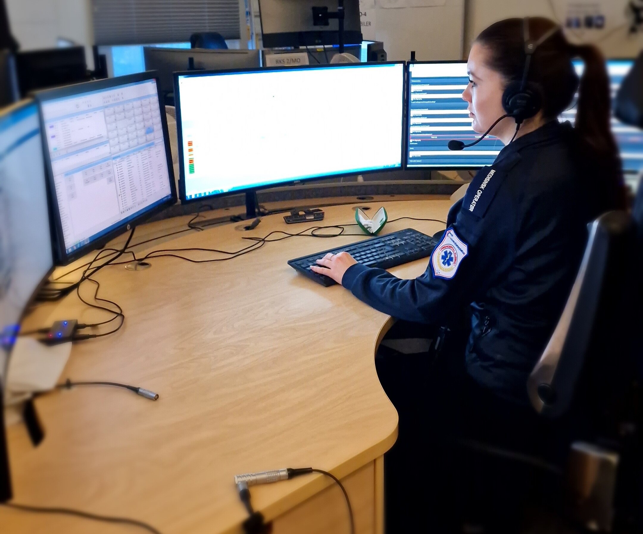 AMK-sentralen Bildet viser en AMK-sykepleier på AMK-sentralen. Hun sitter foran fire store skjermer og svarer på 113-samtaler