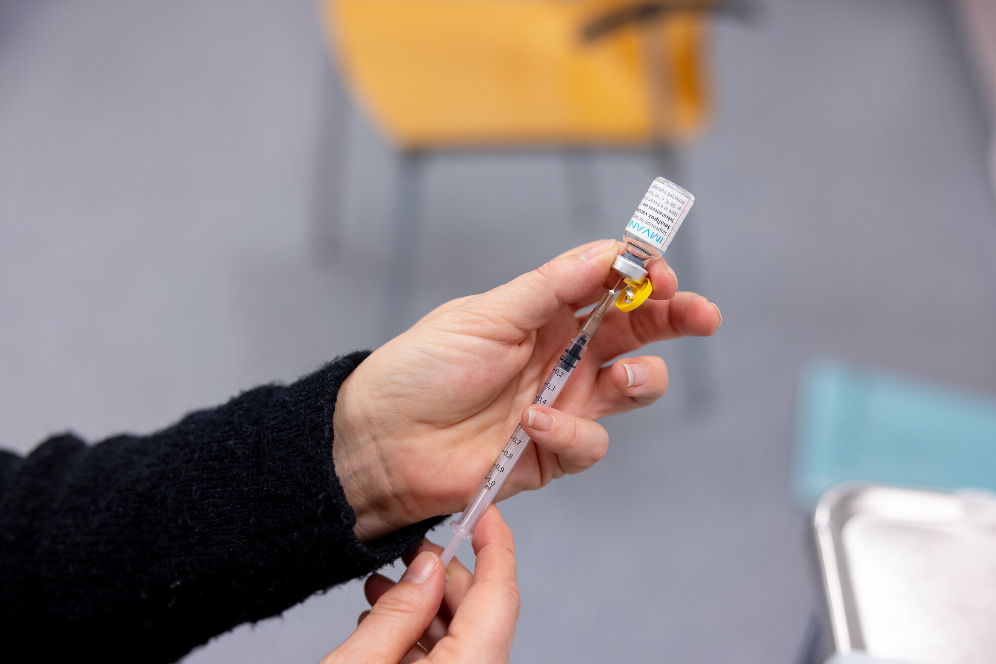 Bildet viser hender som trekker opp en dose apekoppevaksine.