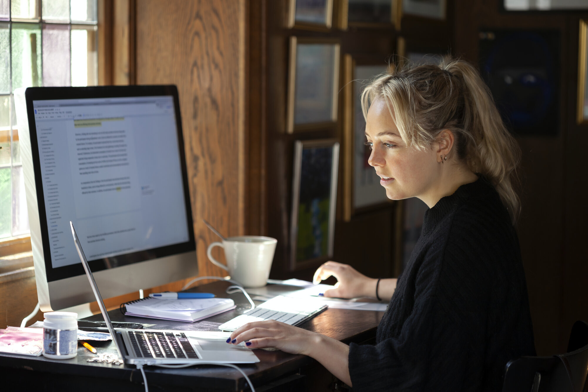 Kvinne som sitter hjemme ved en datamaskin. Bildet viser en kvinne som sitter hjemme ved en datamaskin.