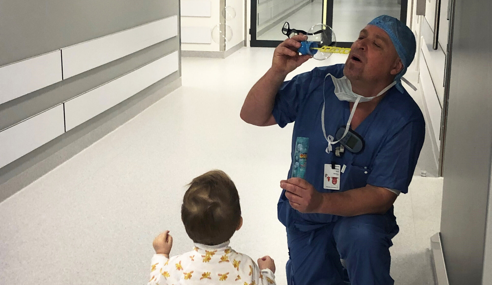 Sykepleier Bildet viser en mannlig sykepleier sammen med et lite barn