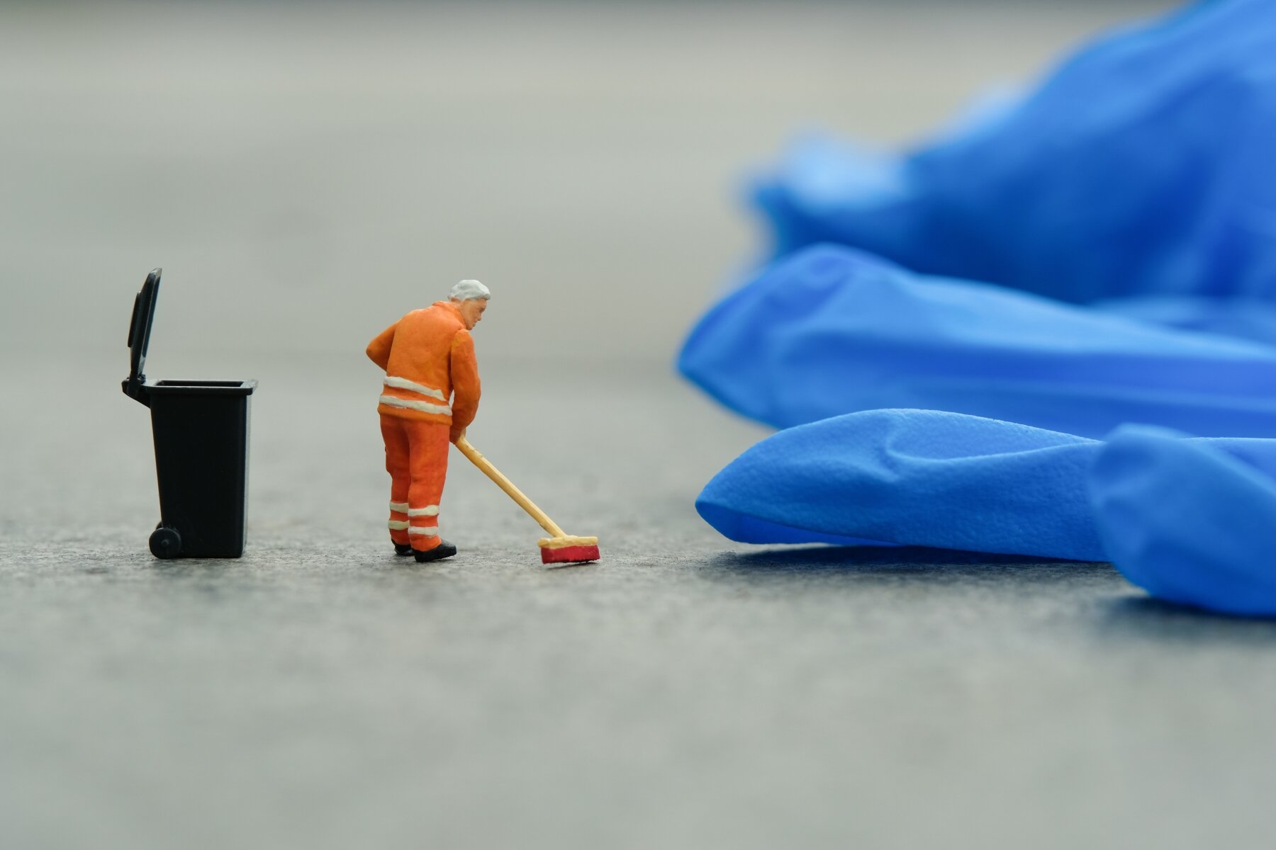 Bildet viser en miniatyrmann som koster opp rundt en engangshanske av plast Bildet viser en miniatyrmann som koster opp rundt en engangshanske av plast