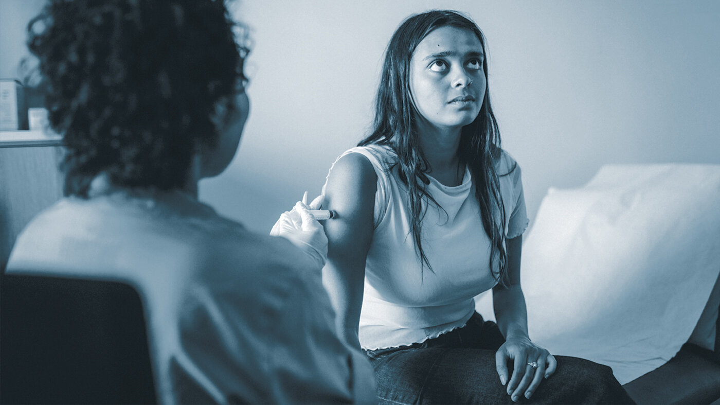 Vaksinering av papirløs migrant Bildet viser en sykepleier som setter en vaksinesprøyte i armen på en ung kvinne