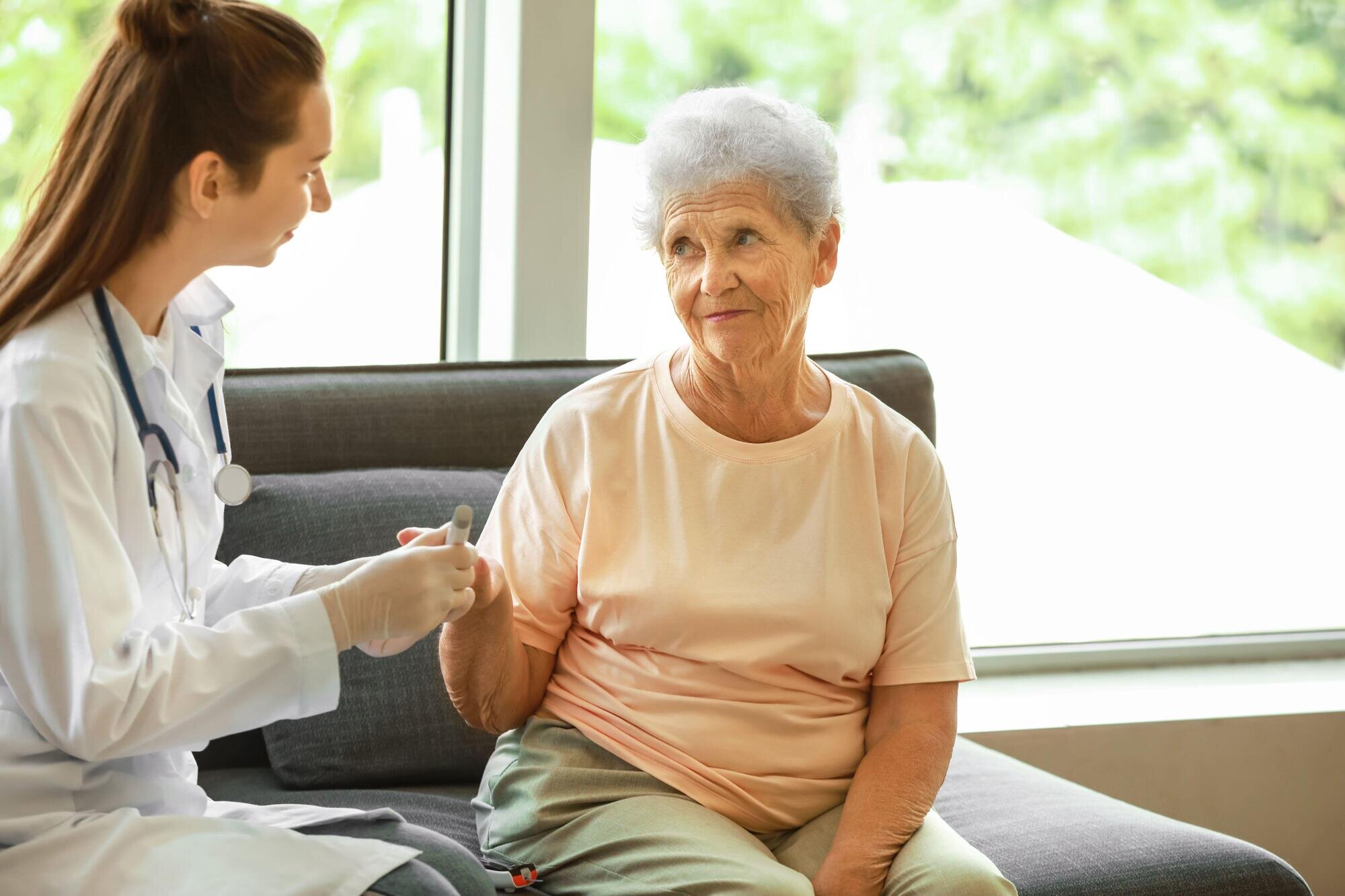 Bildet viser en kvinnelig lege som måler blodsukkeret til en eldre dame