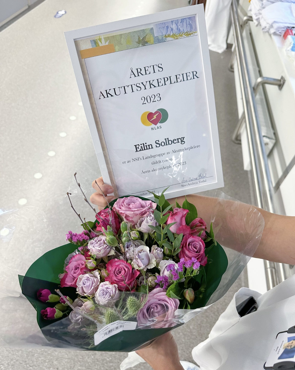 Bildet viser diplom og blomster.