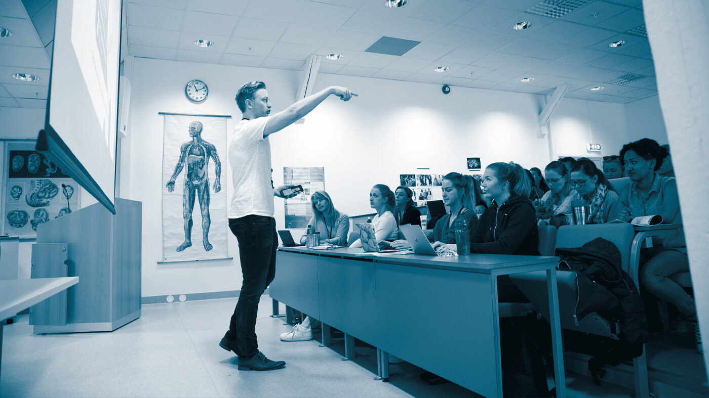 Lecturer and nursing students The photo shows a male lecturer in an auditorium full of female students