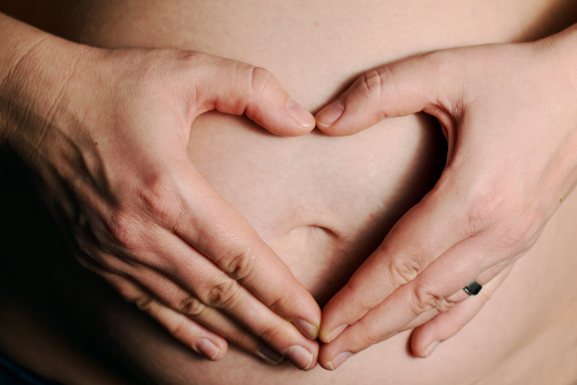 Gravid kvinne viser frem magen sin.