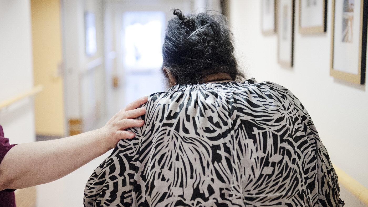 En sykepleier som holder en hånd på skulderen til en kvinne. Bildet viser en sykepleier som holder en hånd på skulderen til en kvinne.