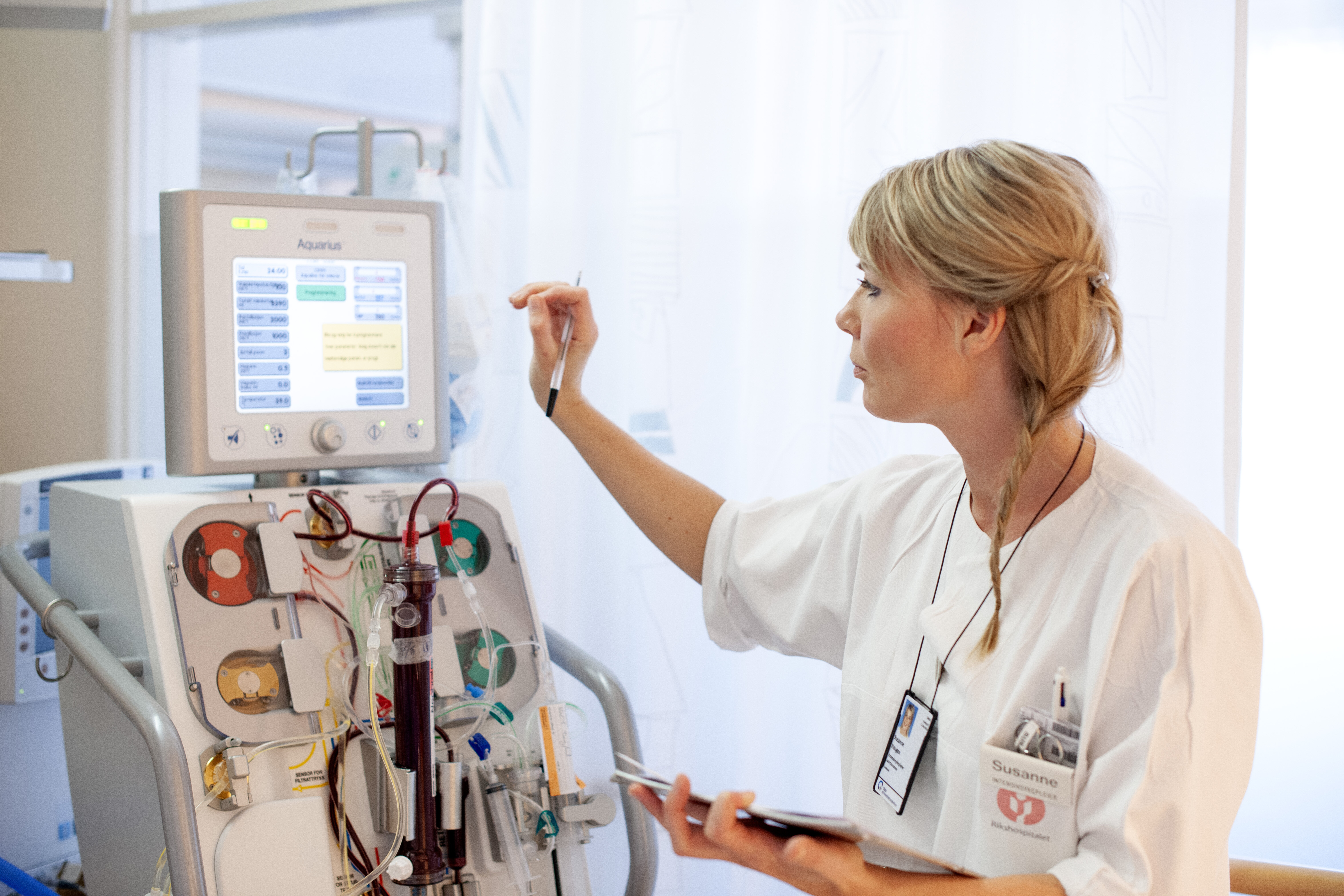 Newly educated intensive care nurse The photo shows an intensive care nurse touching a screen on a machine with tubes and other equipment.