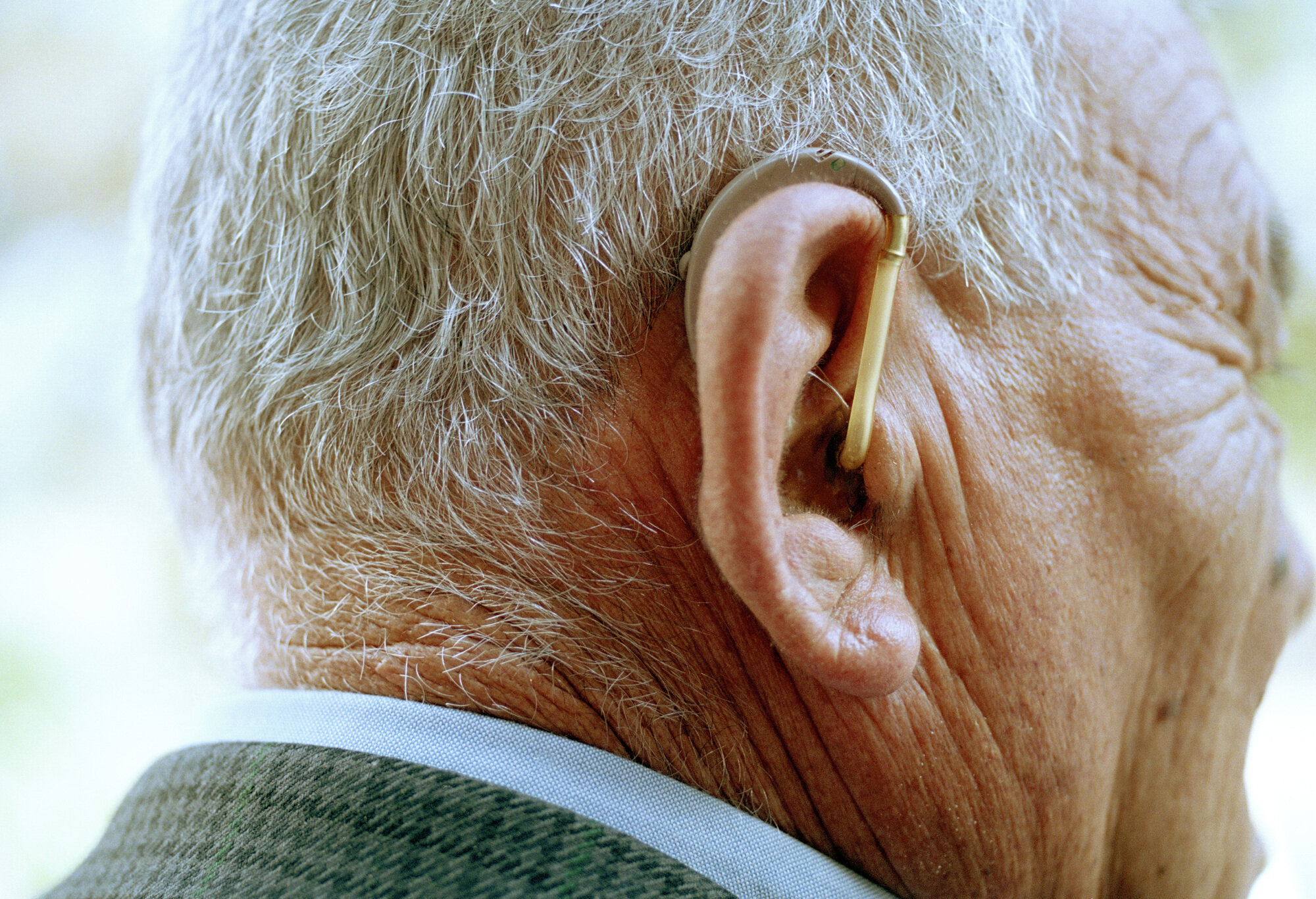 Bildet viser en eldre mann med høreapparat.