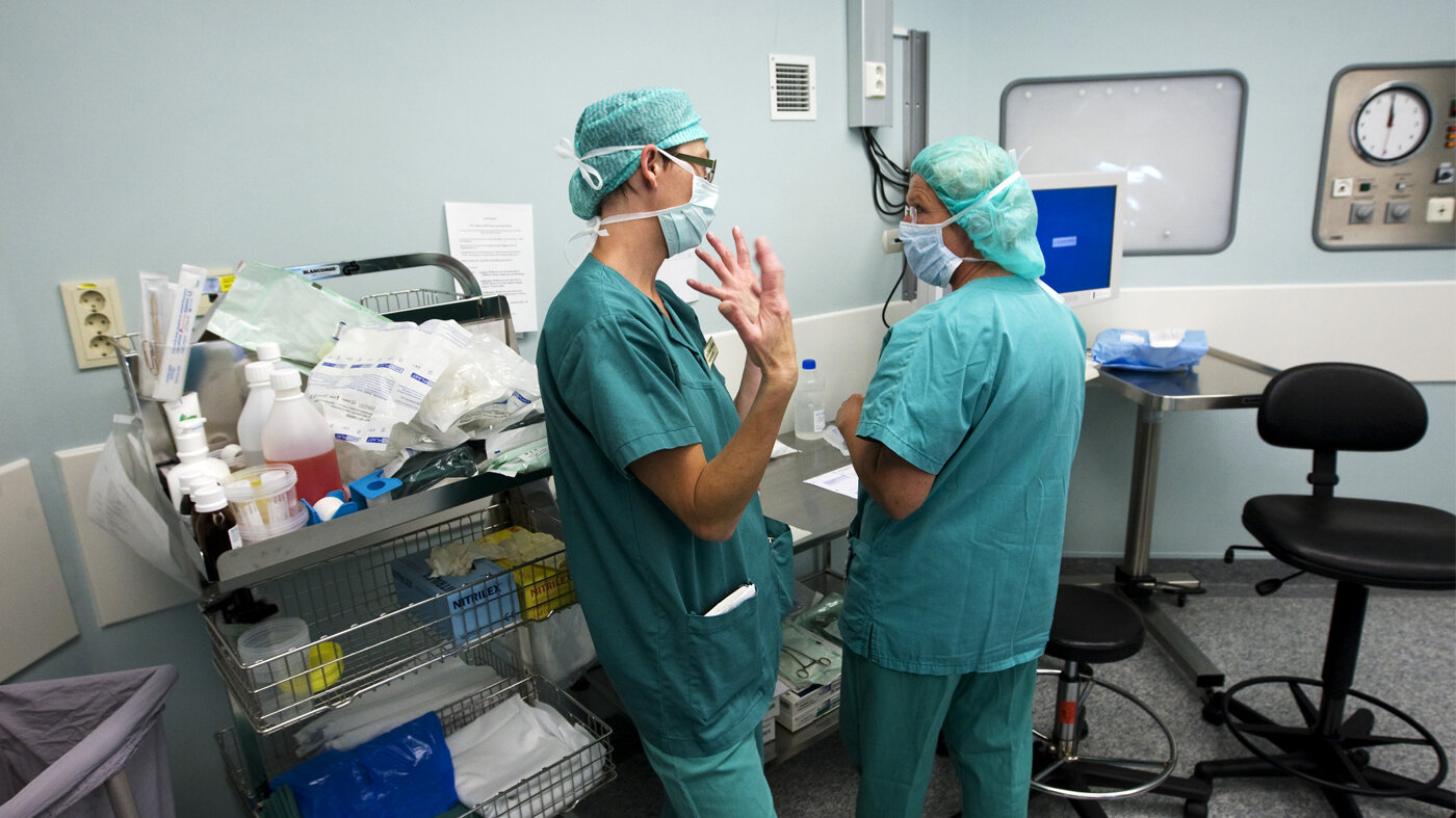 Bildet viser to sykepleiere i dialog på en operasjonsstue. Bildet viser to sykepleiere i dialog på en operasjonsstue.