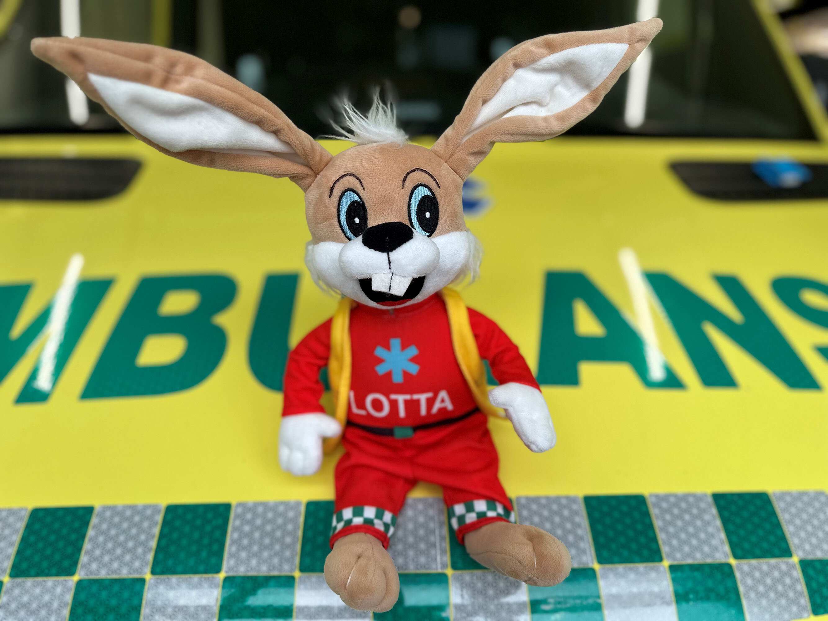 Bilde viser Ambulotta som sitter på panseret på en sykebil. Bilde viser Ambulotta som sitter på panseret på en sykebil.