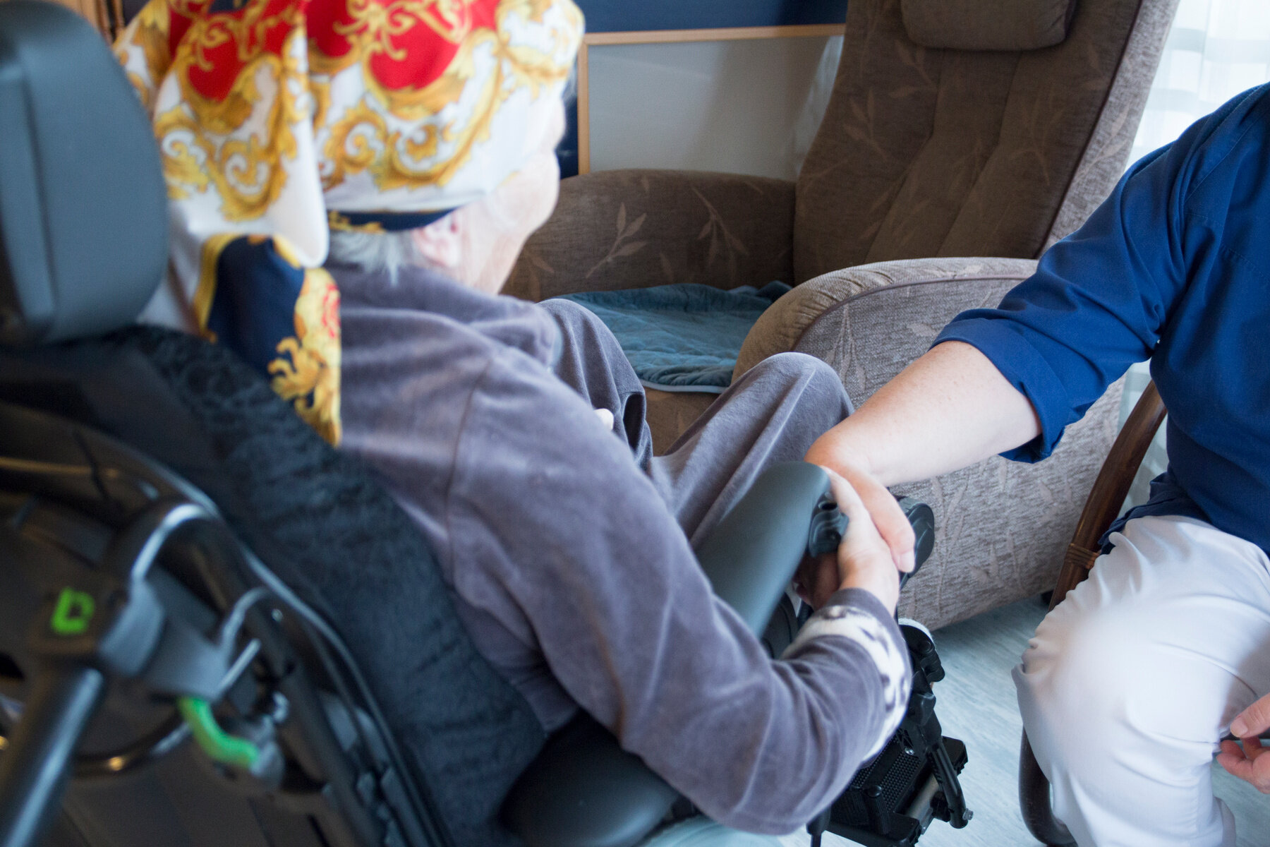 Bilde viser en eldre dame som holder en sykepleier i hånden Bilde viser en eldre dame som holder en sykepleier i hånden