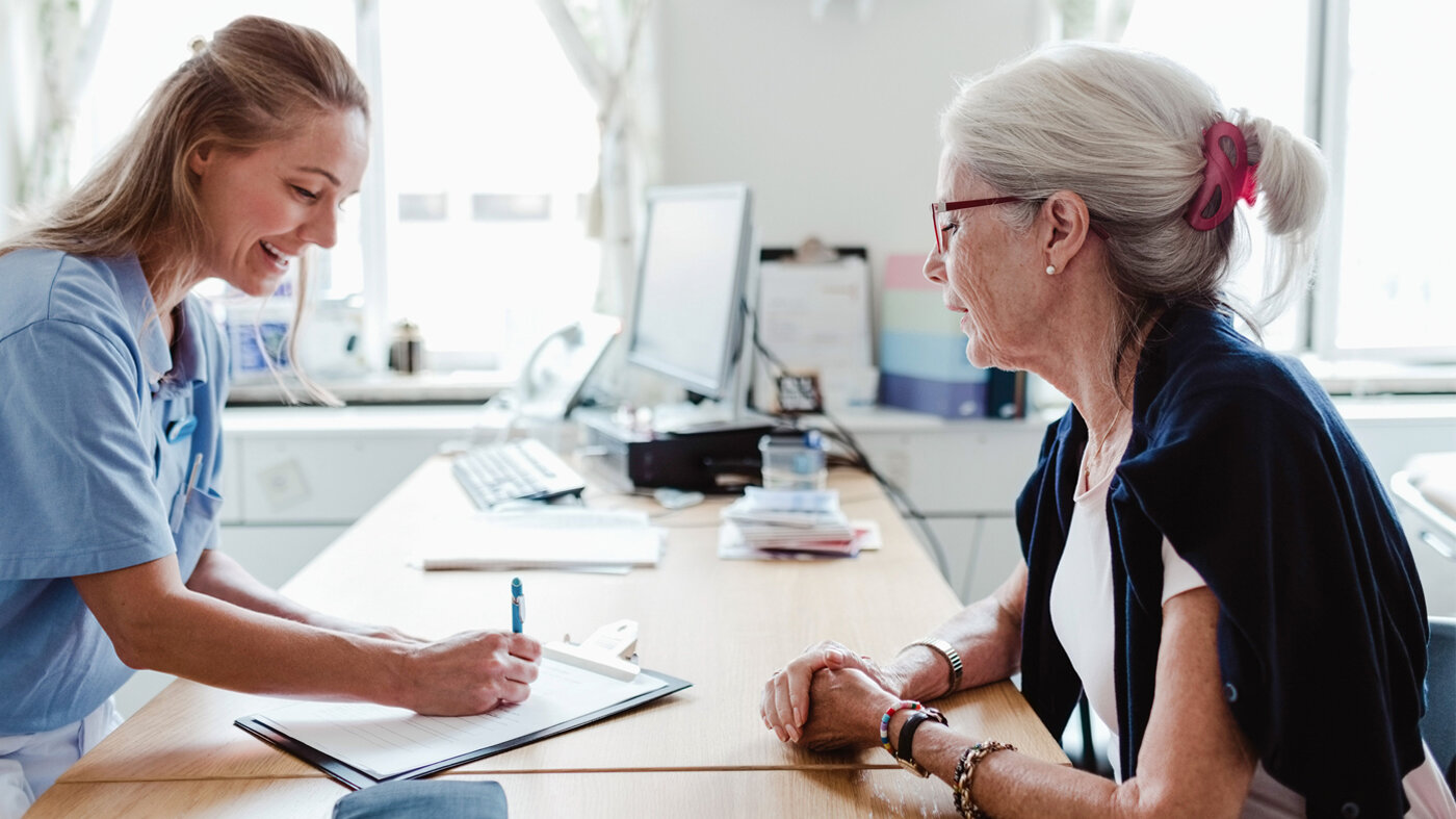 Sykepleier og pasient som fyller ut et skjema. Bildet viser en sykepleier og pasient som fyller ut et skjema.