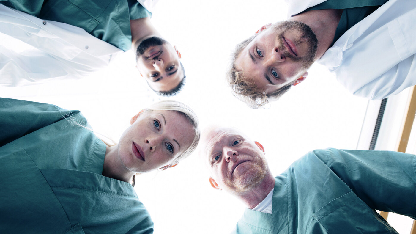 Bildet viser fire sykepleiere som ser ned på en pasient