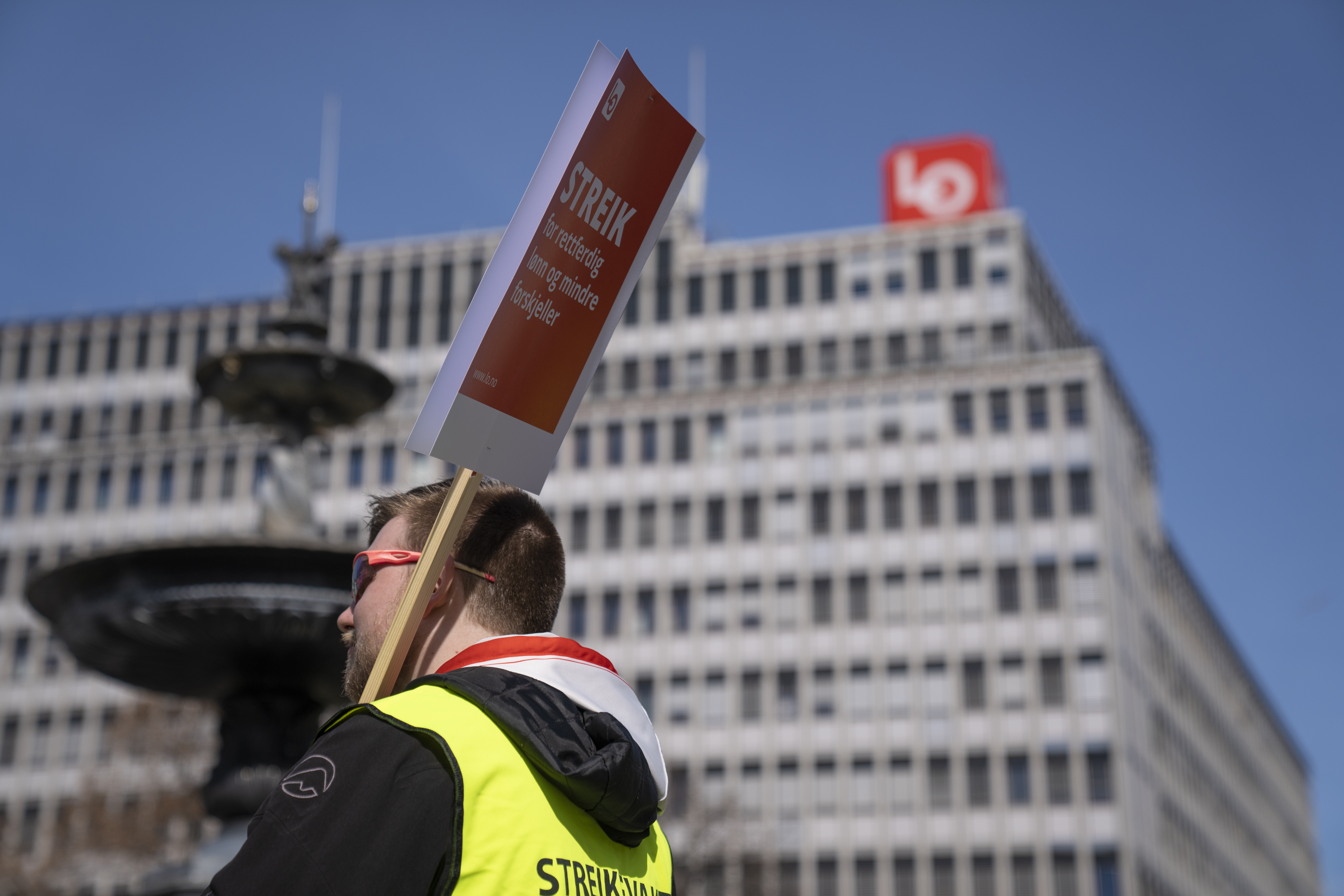 Bildet viser streikende mann med gul vest og plakat