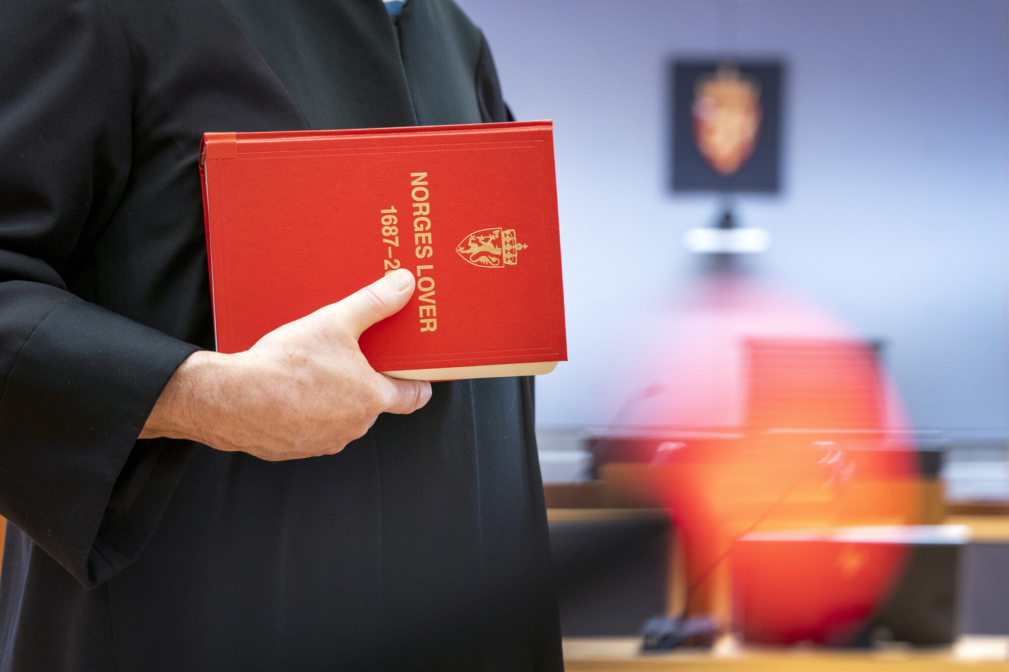 Bildet viser en dommer med Norges lover i hånden.