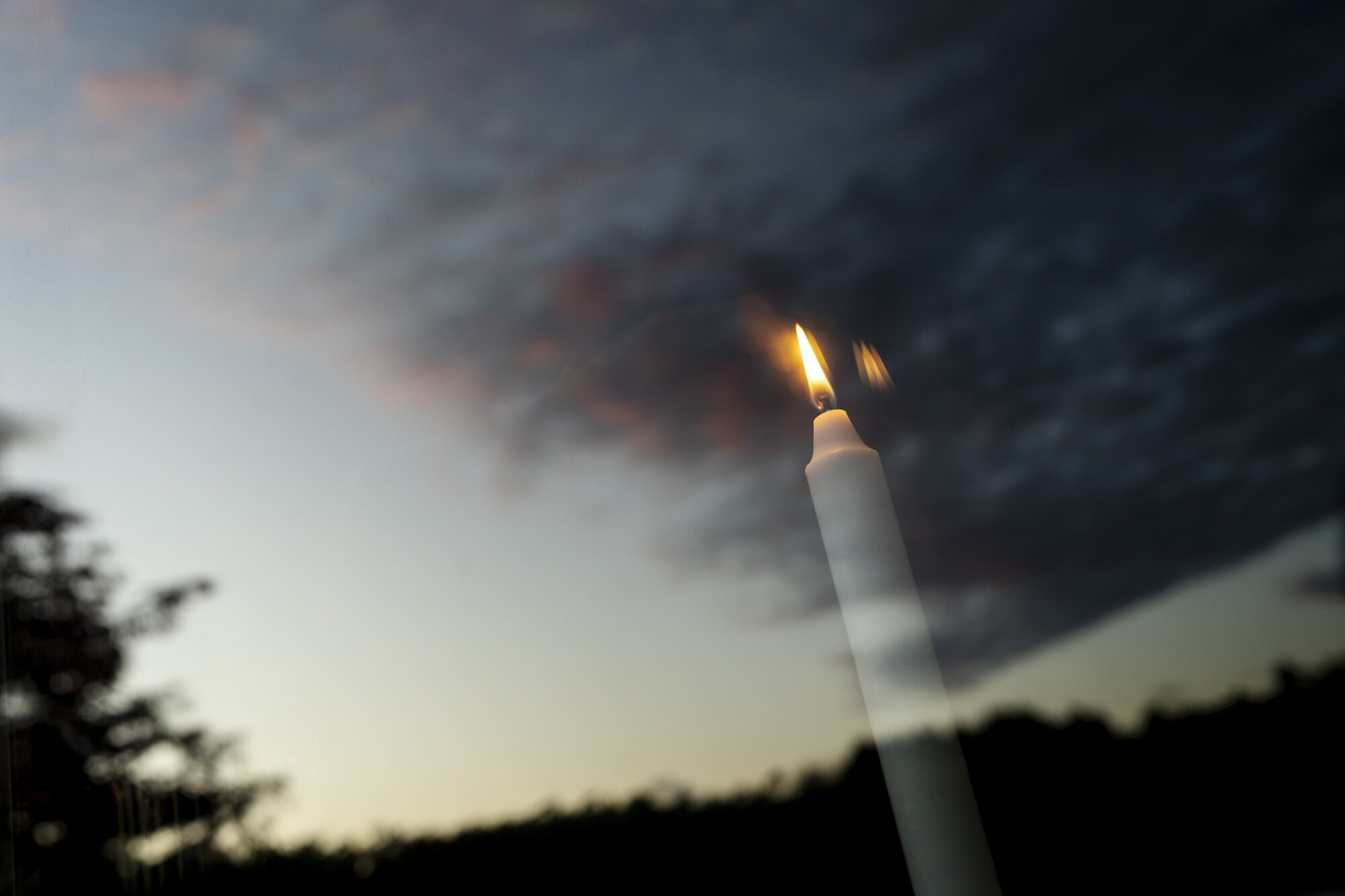 Bildet viser gjenskinnet av et tent lys i et vindu