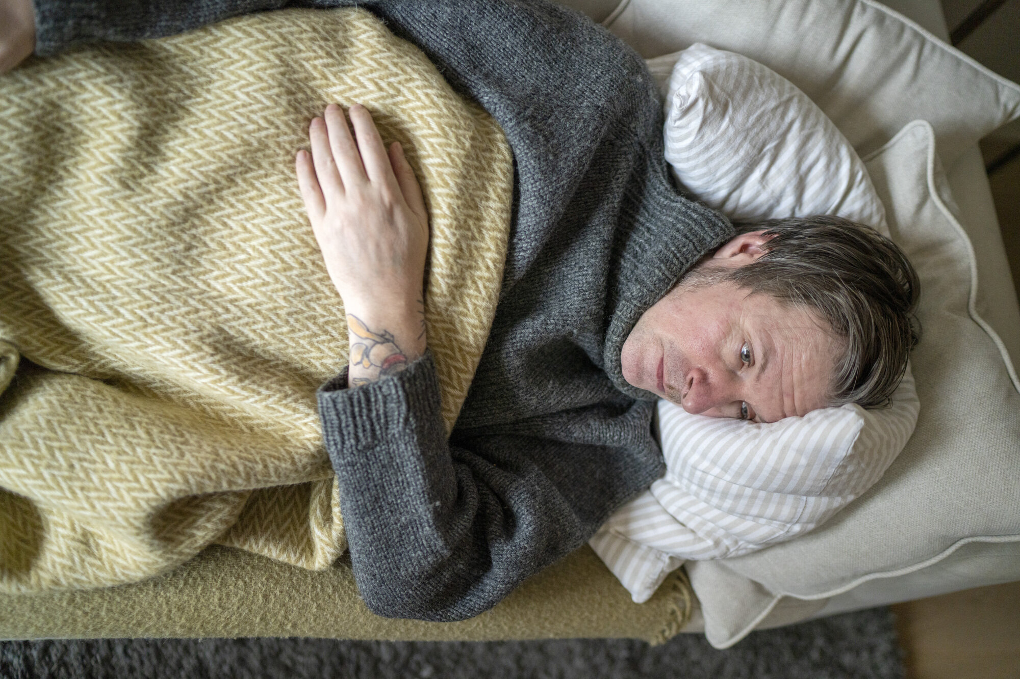 Illustrasjonsbilde av forkjølet mann på sofaen.