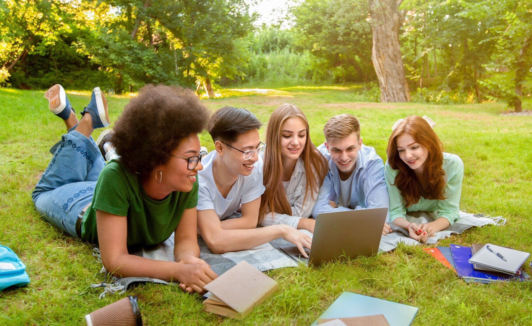 Bildet viser en gjeng studenter som jobber sammen på en laptop utendørs